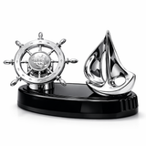 Decorative nautical sculpture with a ship wheel and sailboat on a black base.